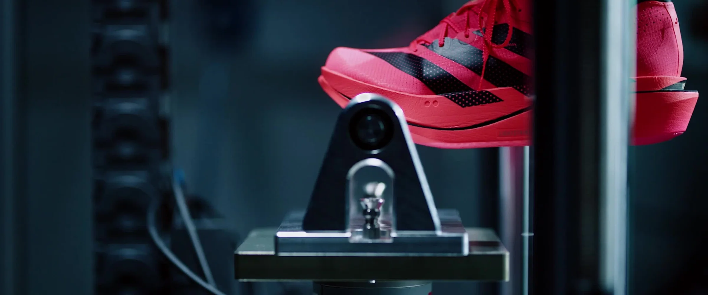 Um adidas Adizero vermelho preso numa máquina de teste, no escuro